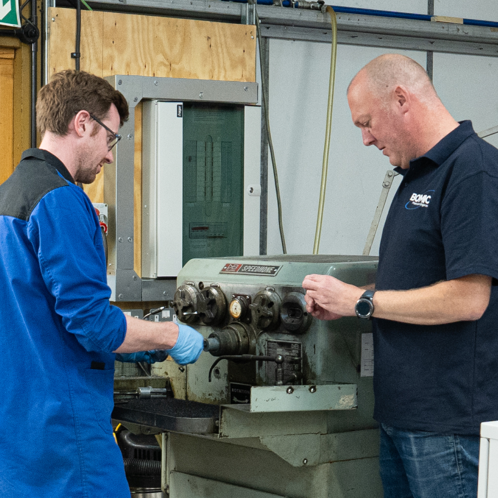 2 men in Bomic precision engineering workshop shown operating a honing and lapping machine